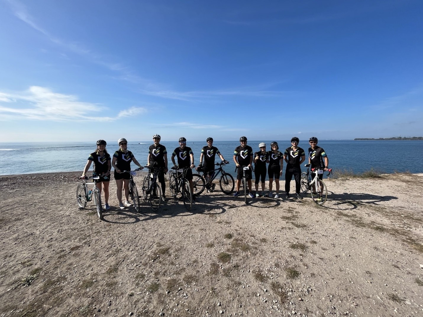 Groupe d’employés de l’OCRI posant avec leur vélo et portant leur maillot de vélo de l’OCRI sur les rives du lac Ontario pendant une activité de financement pour la recherche sur l’autisme